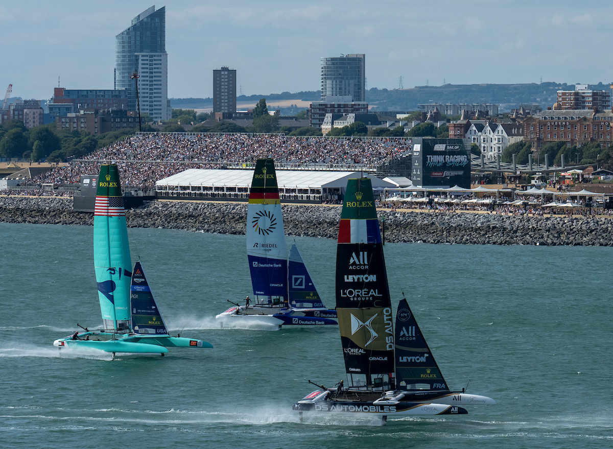 DS Automobiles SailGP Team France driven by Quentin Delapierre leads Germany SailGP Team presented by Deutsche Bank driven by Erik Kosegarten Heil and United States SailGP Team driven by Taylor Canfield past the Grandstand on Race Day 2 of the Emirates Great Britain Sail Grand Prix in Portsmouth, United Kingdom. Sunday 26 July 2026. Rolex SailGP Championship Event 8 2026 Season. Photo: Jon Buckle for SailGP. Handout image supplied by SailGP